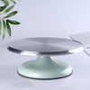 A silver aluminum cake turntable with a light mint green base is shown on a white surface.