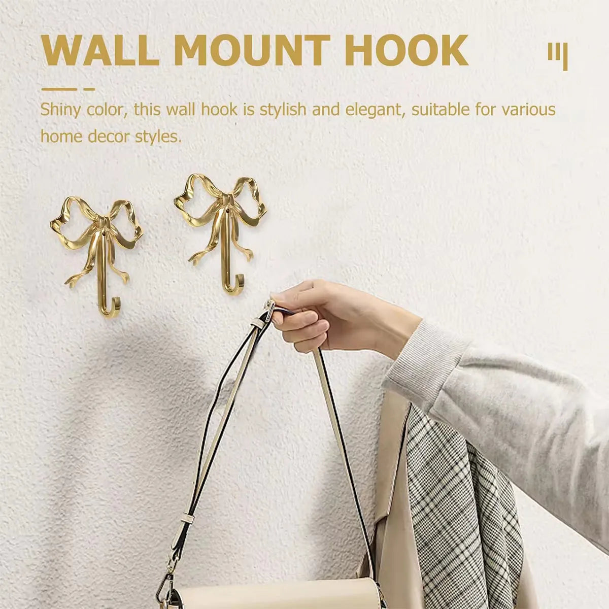 A hand is hanging an elegant brass bowknot wall hook on a white wall for home decor.