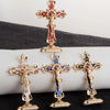 A set of three gold metal crucifix desk crosses with self-adhesive bases displayed on a dark surface.