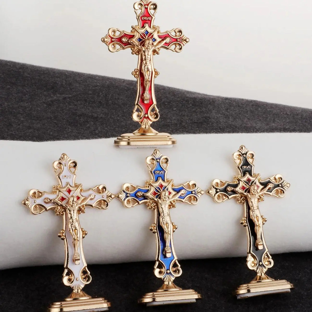 A set of three gold metal crucifix desk crosses with self-adhesive bases displayed on a dark surface.