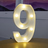 A glowing white LED alphabet letter light shaped like the number 9 resting on a wooden surface.