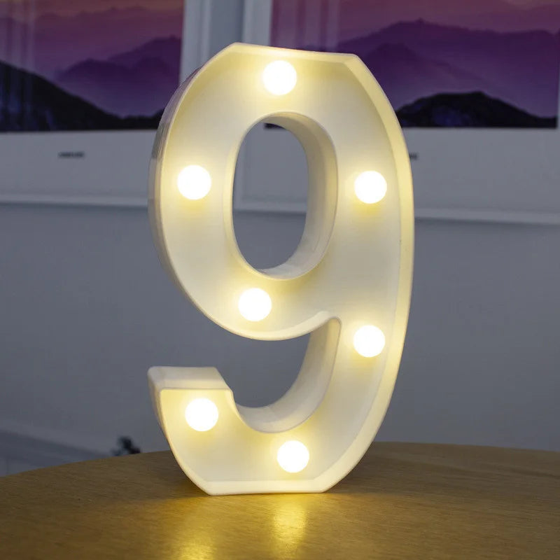 A glowing white LED alphabet letter light shaped like the number 9 resting on a wooden surface.