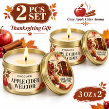 A set of two Evoduck Apple Cider Welcome scented candles in gold tins, presented as a Thanksgiving gift.
