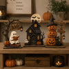 A wooden Halloween decor set featuring ghost, black cat, and pumpkin figurines displayed on a shelf.