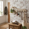 Rustic wooden key holder with a heart accent and four hooks mounted on a white brick wall.