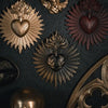 A collection of ornate gold and copper wall plaques featuring sacred heart designs with radiating sunburst patterns.