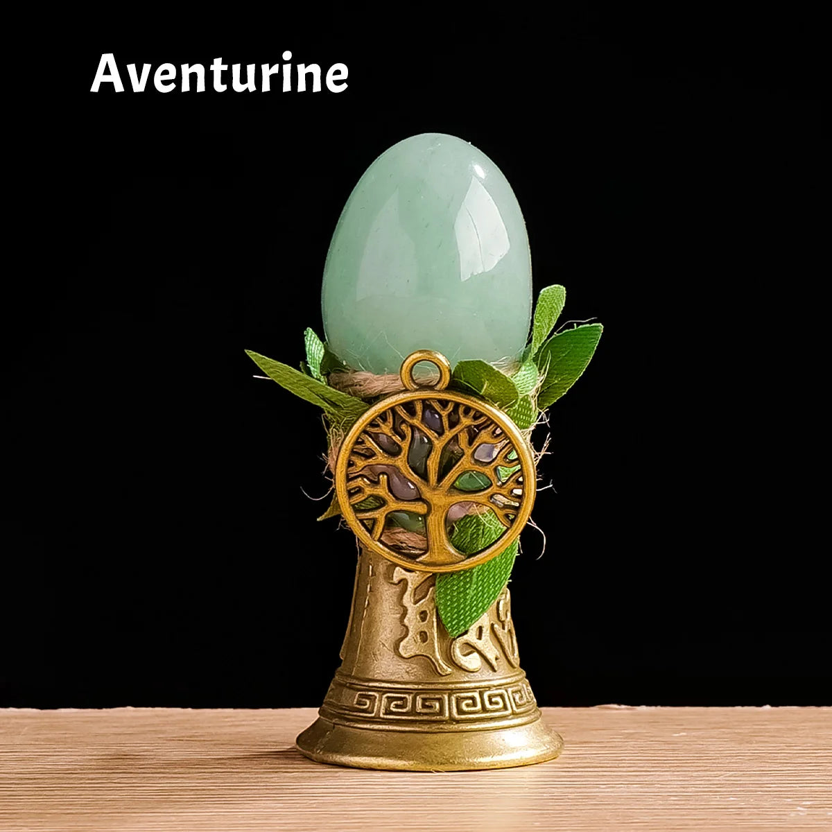 A smooth, light green Aventurine crystal is displayed atop a brass tree of life chime.