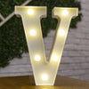 A large, illuminated letter V made of warm white LED lights standing on a wooden surface.
