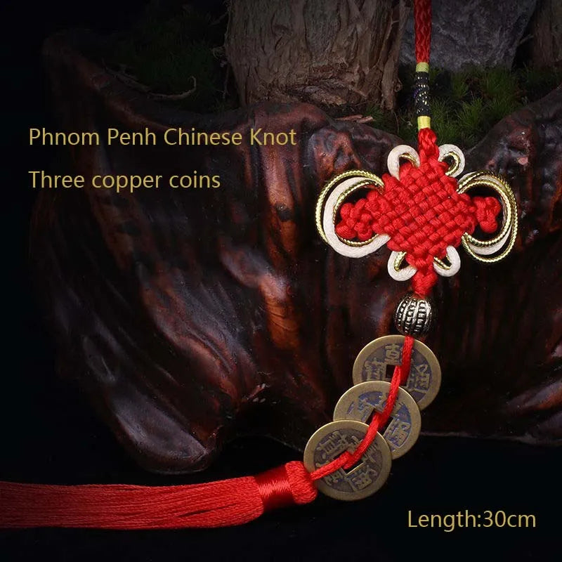 Red thread pendant featuring a Chinese knot and three copper coins on a dark background.
