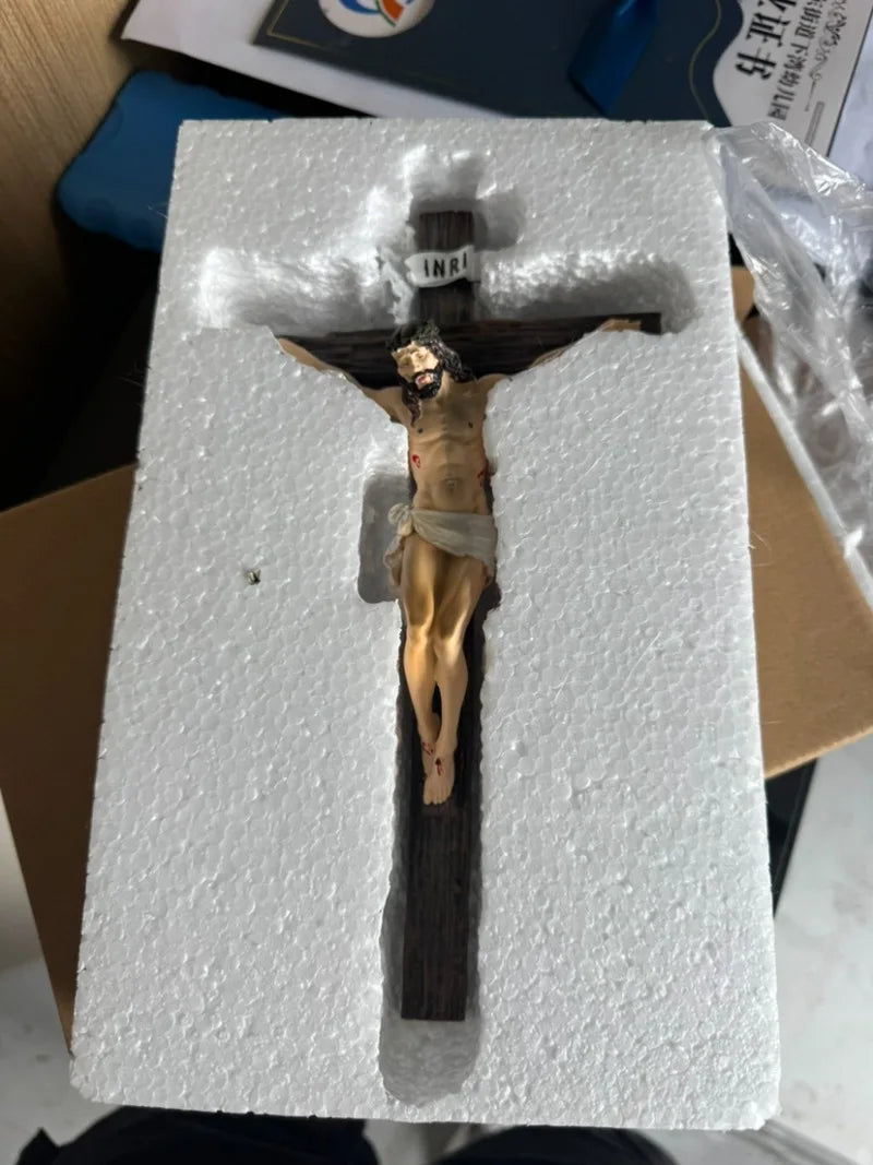 A resin sculpture of the crucifix, depicting Jesus on the cross, is displayed in a white foam block.