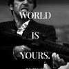 A black and white photo of Tony Montana with a gun, featuring the text The World Is Yours.