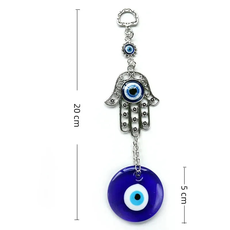 A silver hamsa hand amulet with blue evil eye designs and a round blue stone pendant.