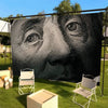 A large black and white portrait of Benjamin Franklin's face displayed on a banner in an outdoor setting.