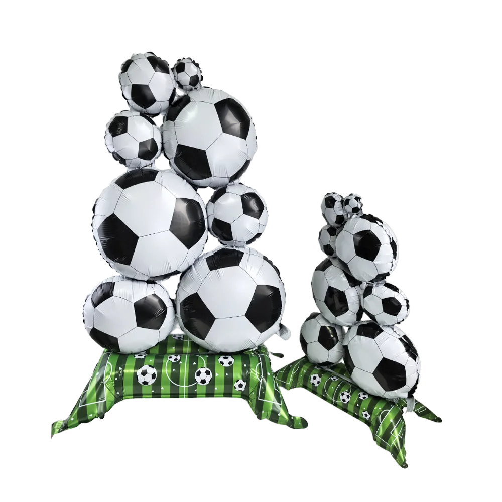 A stack of white and black soccer balls decorated with green ribbon, used as party decor.