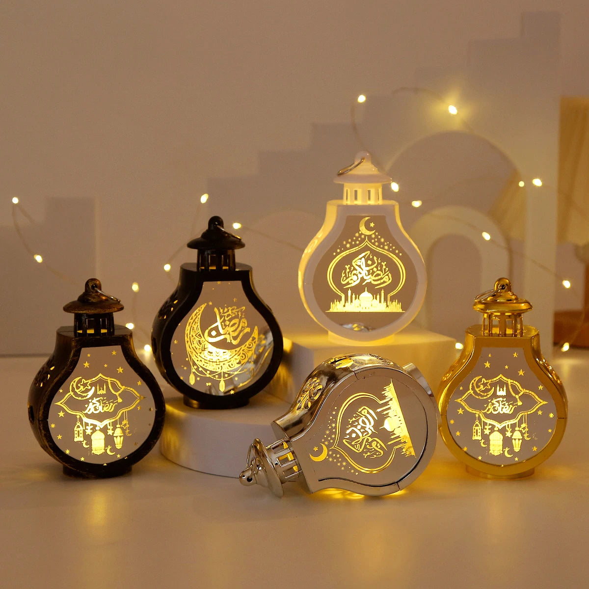 A collection of elegant LED star and moon lanterns glowing with warm light on a white surface.