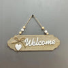 Rustic wooden welcome sign with the word Welcome carved into the wood and tied with twine.