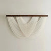 Bohemian macrame wall tapestry featuring white knotted cords suspended from a dark wooden bar.