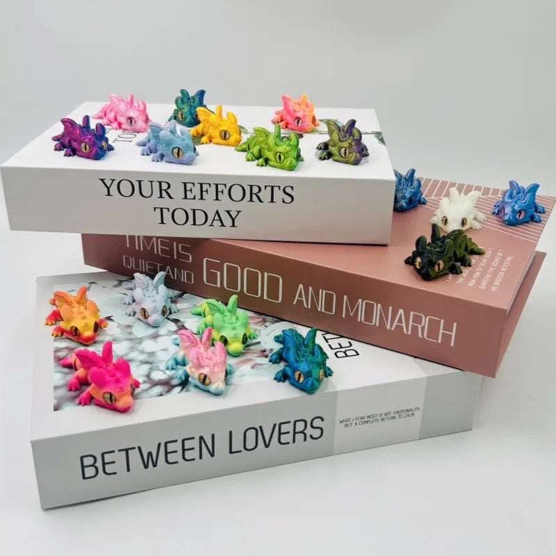 A collection of colorful articulated baby dragon figurines displayed on stacked boxes with text like Your Efforts Today and B