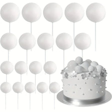 A display of twenty white foam ball cake toppers on individual sticks arranged above a silver cake plate.