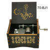 A black wooden music box with a lid featuring an anime character and a silver key.