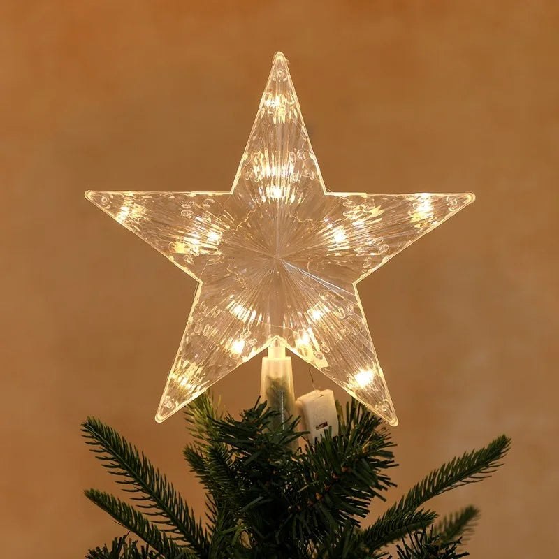 A sparkling LED Christmas tree star topper with a warm white glow resting on a green pine branch.