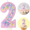 A pink glitter number 2 candle and a cupcake candle shaped like the number 2 for a birthday celebration