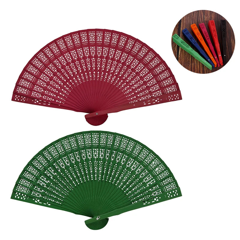 A red hand carved bamboo folding fan displayed next to a green one and several colored fans.