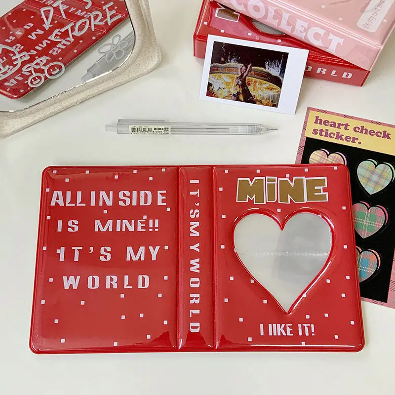 A red multi-size photo album titled Mine with a heart design, next to other photo albums and a pencil.
