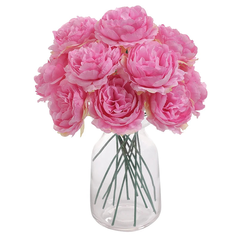A bouquet of six pink silk peony flowers arranged in a clear glass vase.