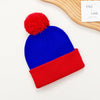 A knitted beanie set featuring royal blue and red colors with a red pom-pom on top.