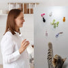 A woman is placing magnetic glass flower vases on a refrigerator door for decor.