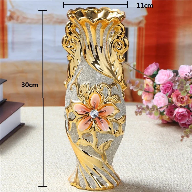 Gold-plated ceramic tabletop vase with ornate scrollwork and a central pink flower design.