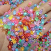 A hand holds a pile of glow-in-the-dark resin turtle figurines in various bright colors for crafts.