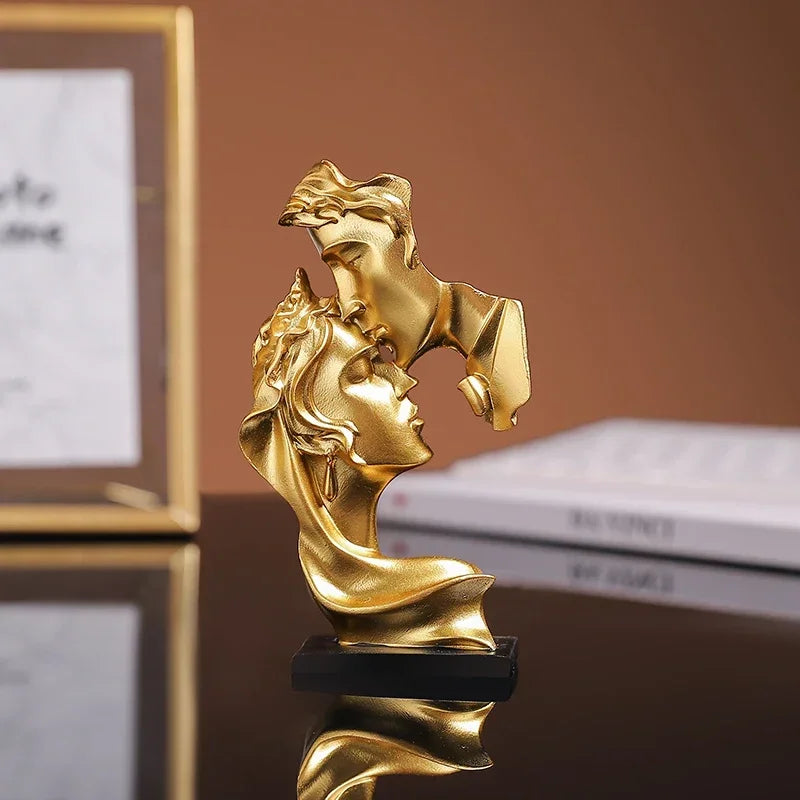 Statue en résine dorée de deux profils s'étreignant, se reflétant sur une surface sombre.