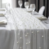 White pearl gauze decorative table flag with beaded trim draped over a white tablecloth.
