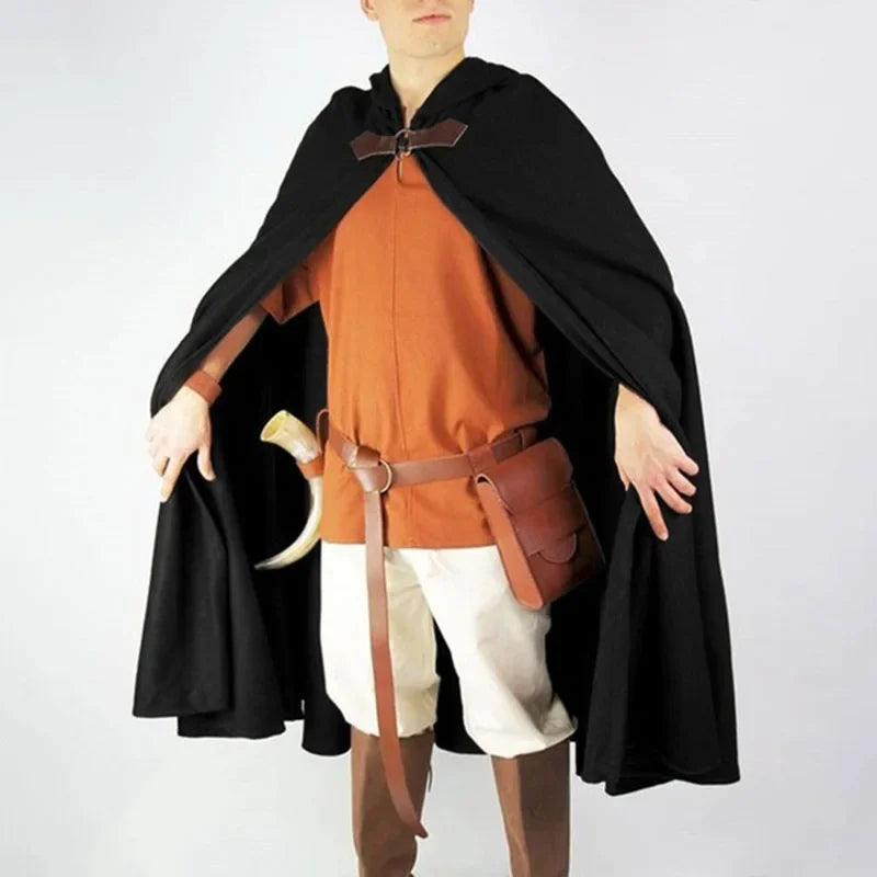 A male model wearing an orange tunic, white pants, and a black velvet hooded cloak with brown leather accents.