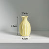A light yellow ceramic mini vase with a narrow neck and rounded body, shown against a neutral background.