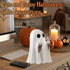 A white ghost figurine with a sassy hand gesture decor on a wooden desk surrounded by pumpkins and computer accessories.