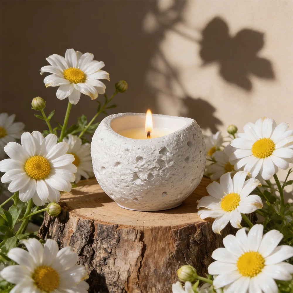 White textured silicone mold for candles, resin, and concrete resting on a wooden log surrounded by white daisies.
