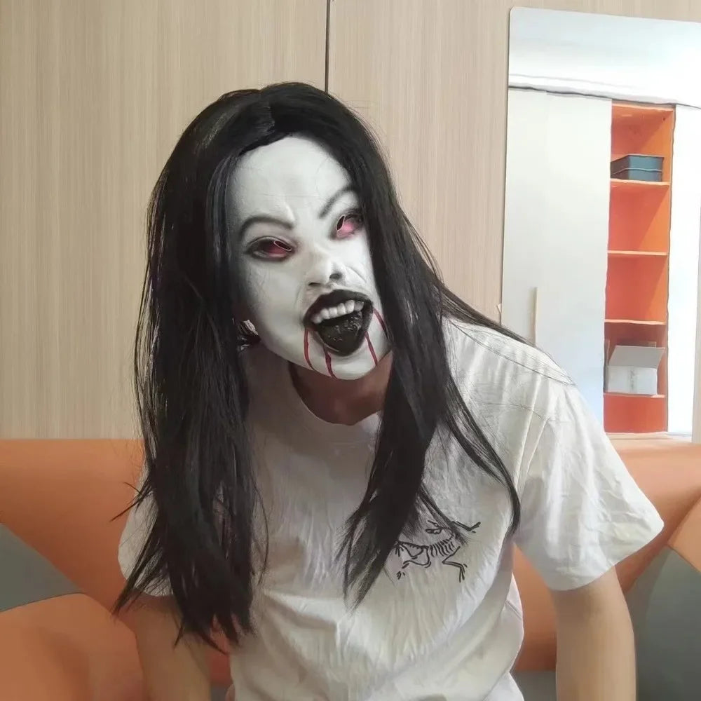A person wearing a white latex horror mask with exaggerated features and long black hair.