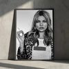 A black and white portrait of Kate Moss with long wavy hair wearing a leopard print jacket.