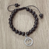 A handmade beaded bracelet with natural black stones and a silver zodiac sign charm