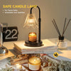 A black candle lamp with a glass shade sits on a white surface next to candles and books.
