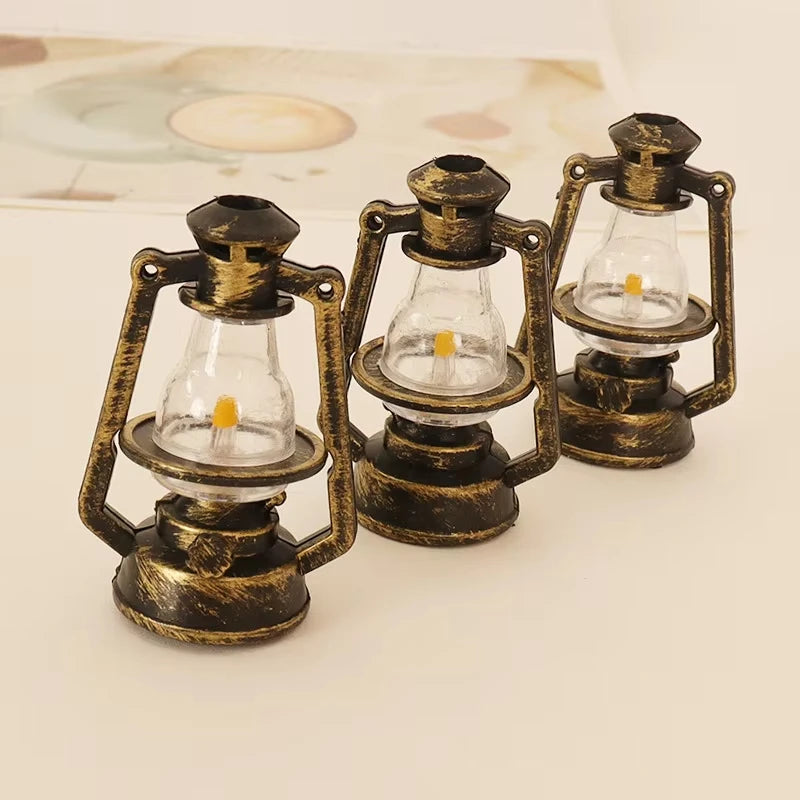 A set of three vintage ceramic miniature lanterns with brass frames and glass bulbs for dollhouse décor.