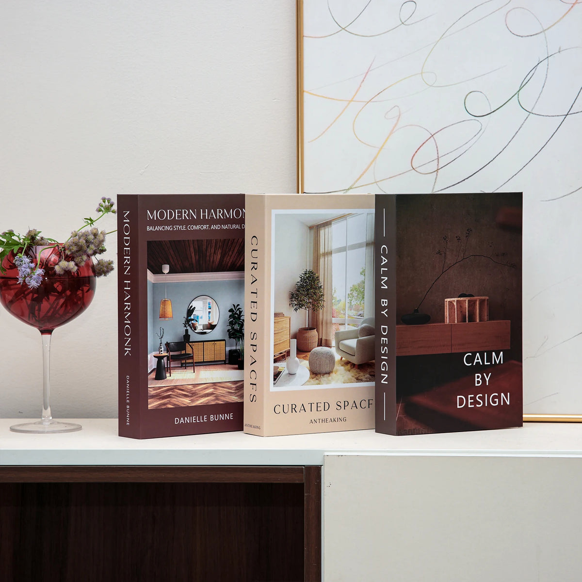 A set of three hardcover books titled Modern Harmony Curated Spaces and Calm by Design displayed on a white surface.