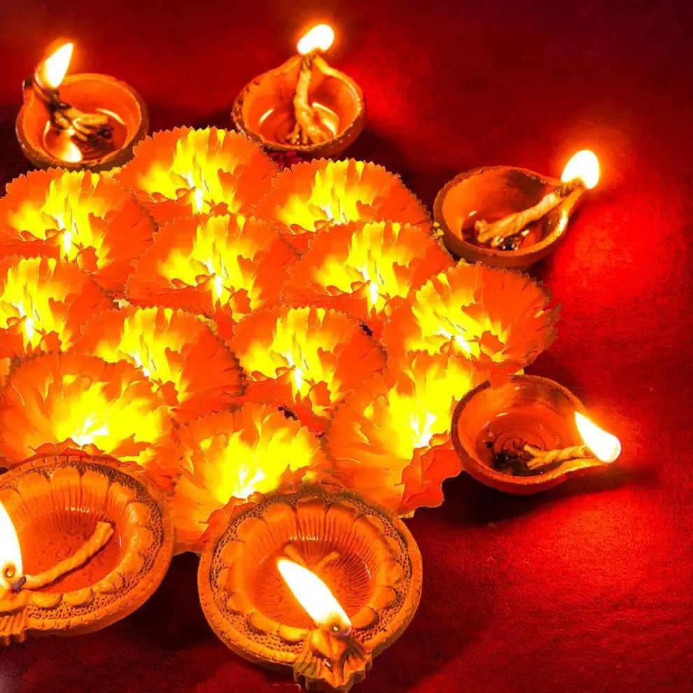 A close-up of numerous glowing orange marigold oil lamps arranged on a red surface.