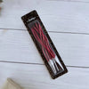 A package of long thin red spiral birthday candles displayed on a white wooden surface.