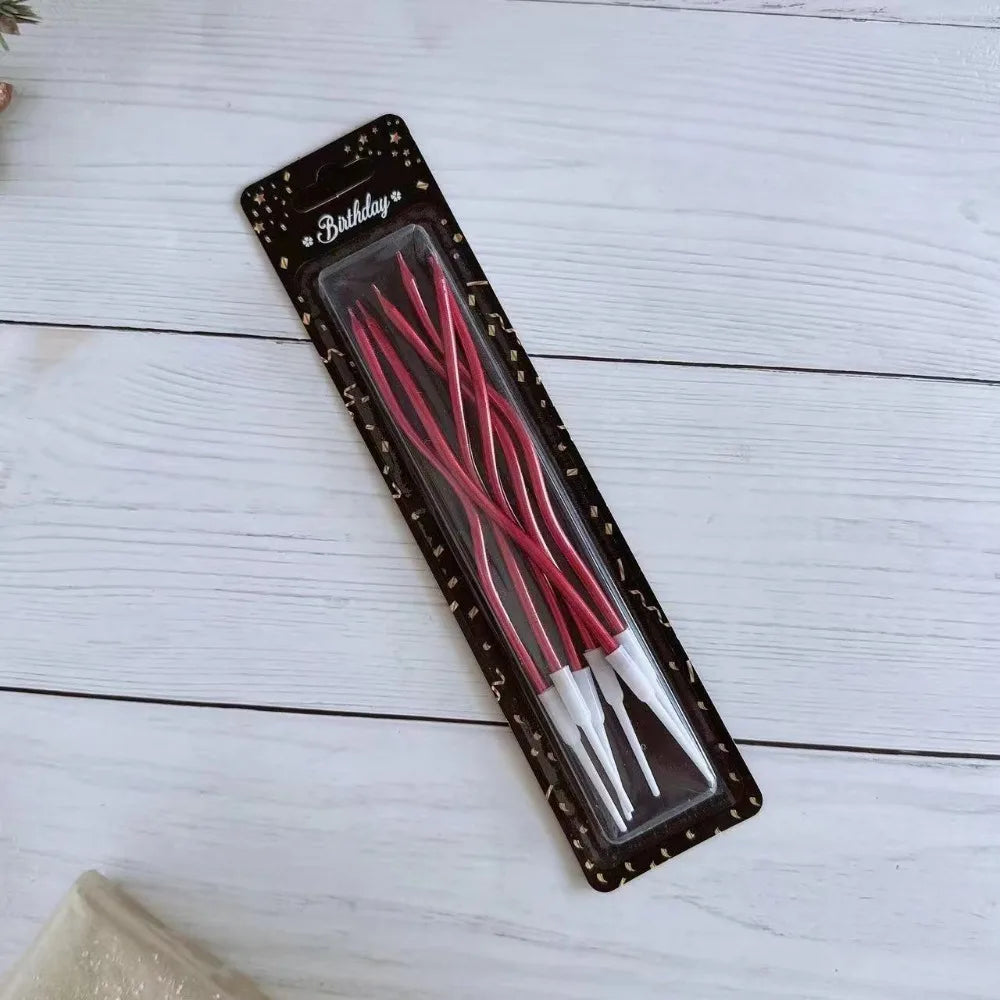 A package of long thin red spiral birthday candles displayed on a white wooden surface.