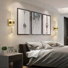 Modern bubble crystal LED wall sconces illuminating a bedroom wall with framed art.