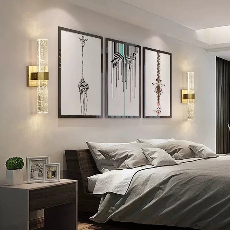 Modern bubble crystal LED wall sconces illuminating a bedroom wall with framed art.